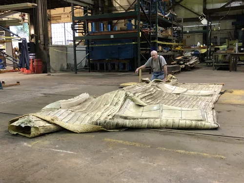 A worker examining the cast-concrete facade panel laid flat in the fabrication shop