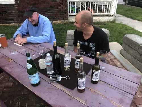 Two friends sharing a meal at a picnic table during a Crooked House project event